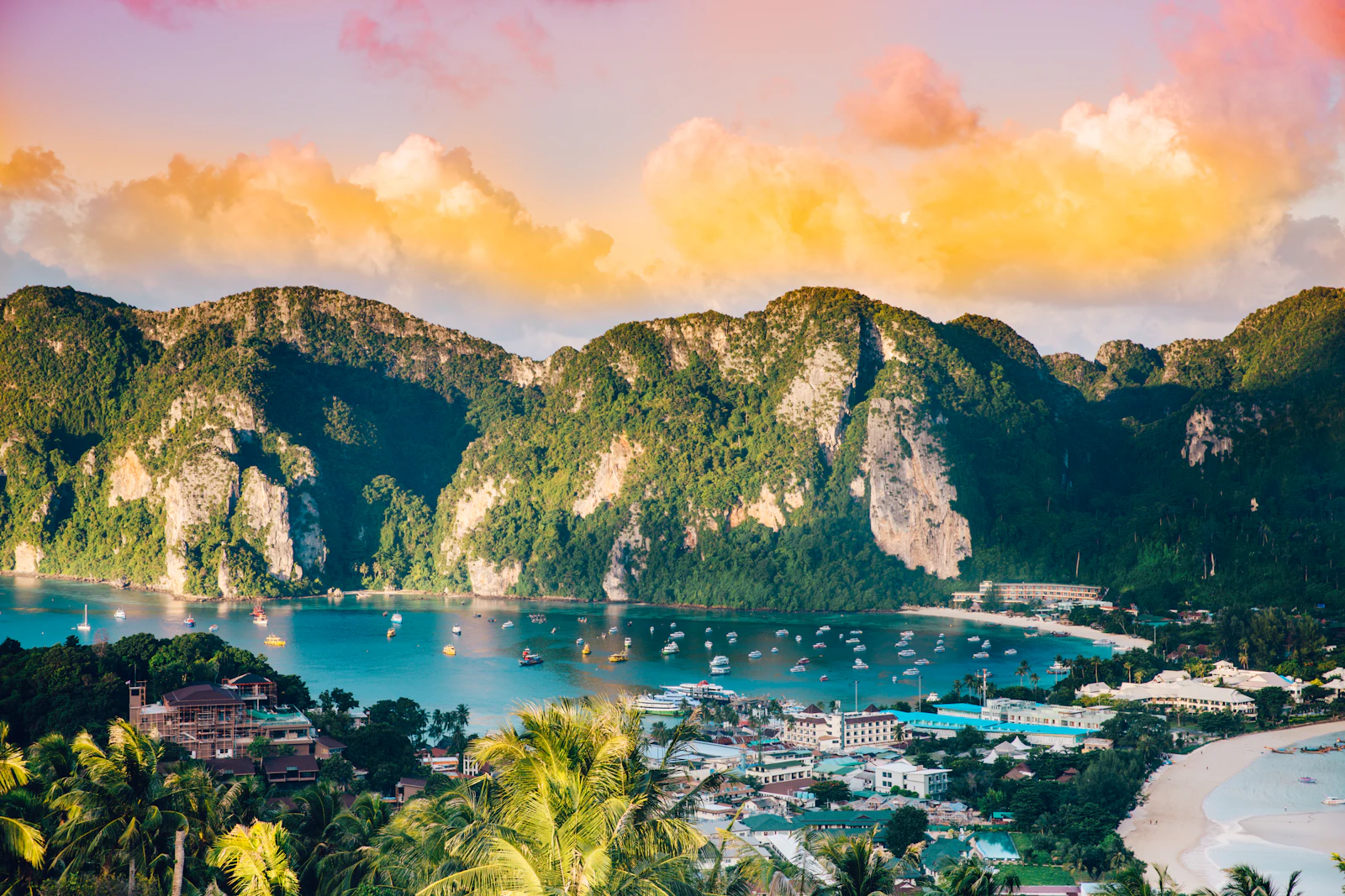 Boats in the bay at Phi Phi Island below green hills at sunrise