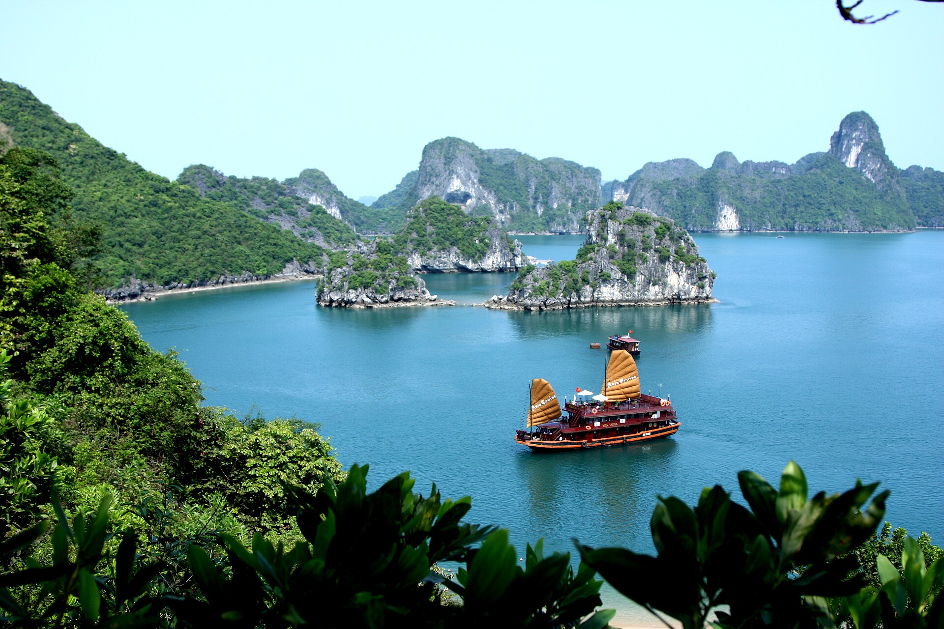 A red-sailed cruise boat among the islands of Ha Long Bay