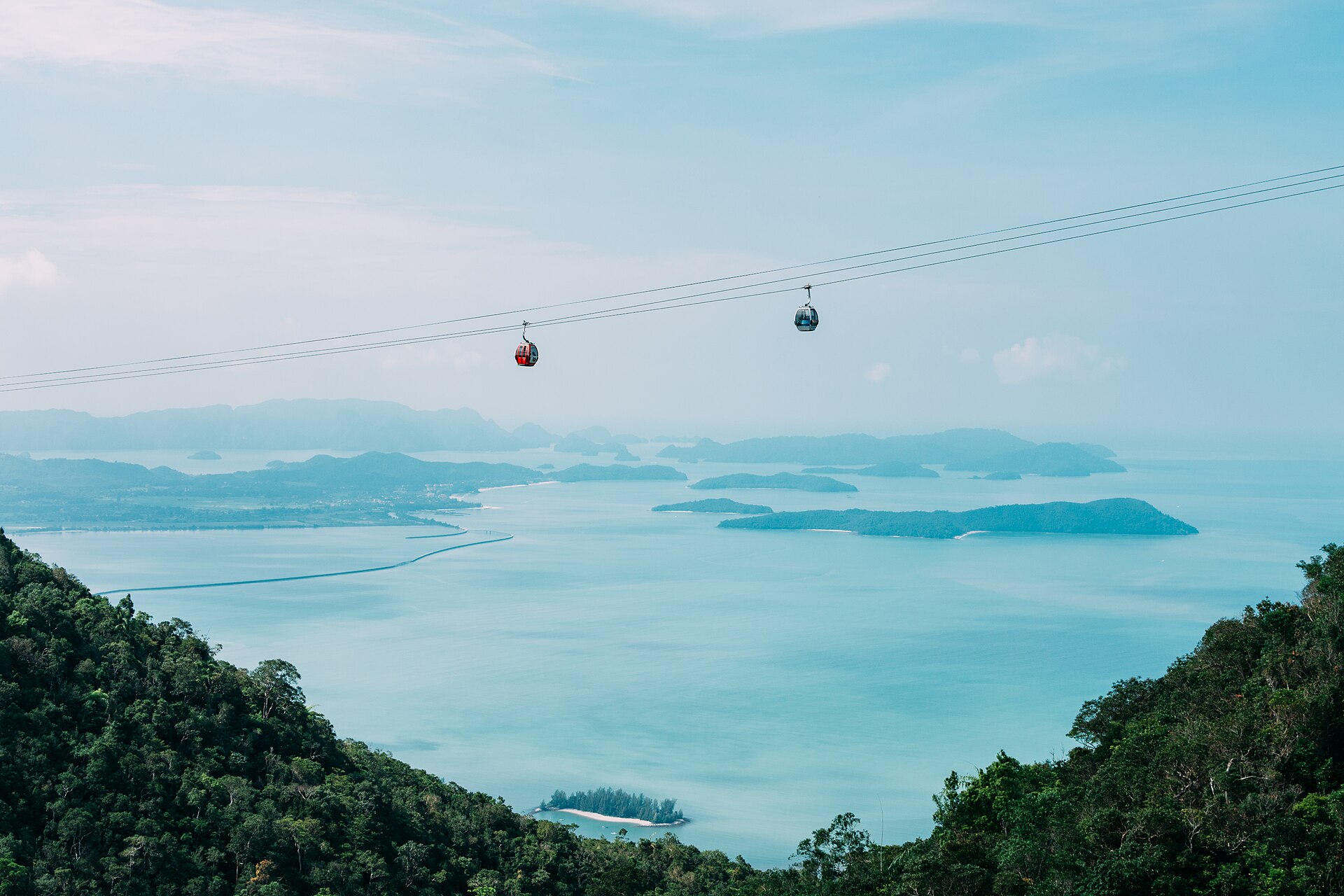 Two cable car gondolas high above the forest, the sea and the islands of Langkawi